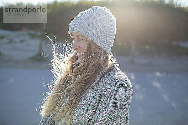 Schöne glückliche junge Frau in stricken Hut auf sonnigen Strand