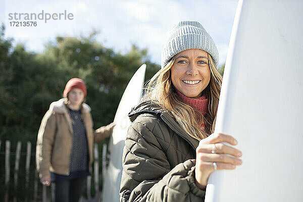 Porträt glücklich junge weibliche Surferin mit Surfbrett