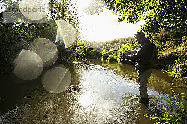 Mann Fliegenfischen am sonnigen idyllischen Fluss