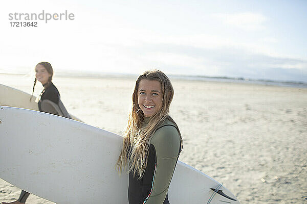 Porträt glücklich junge weibliche Surfer mit Surfbrett auf sonnigen Strand