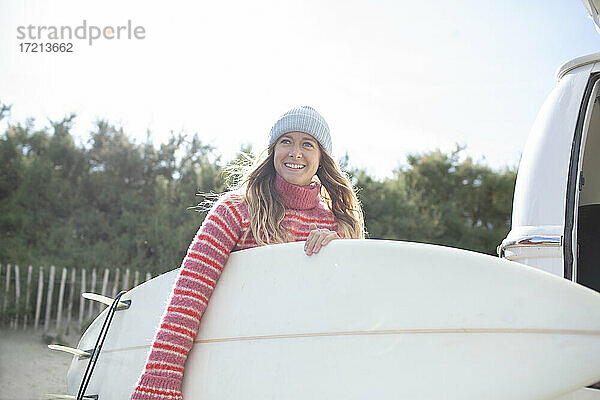 Porträt glücklich junge weibliche Surferin hält Surfbrett