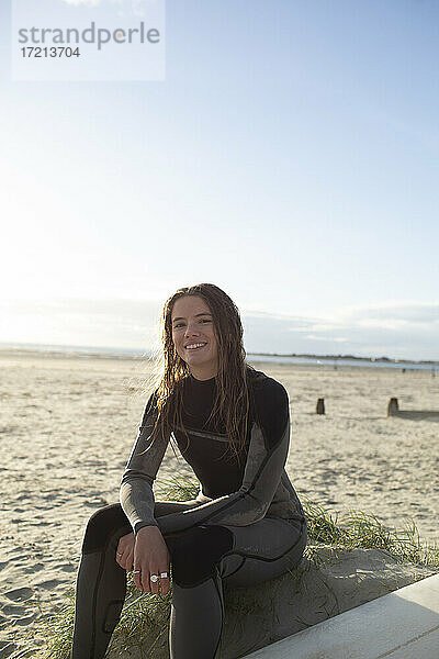 Porträt selbstbewusst schöne junge weibliche Surferin im Neoprenanzug am Strand