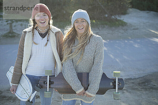 Porträt glückliche junge Frauen Freunde in stricken Mützen mit Skateboards