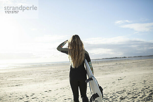 Junge weibliche Surfer mit Surfbrett auf sonnigen ruhigen Sommerstrand