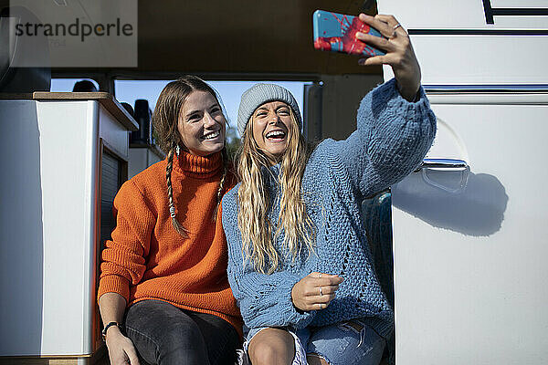 Glückliche junge Frauen Freunde nehmen Selfie in sonnigen Camper van Türöffnung