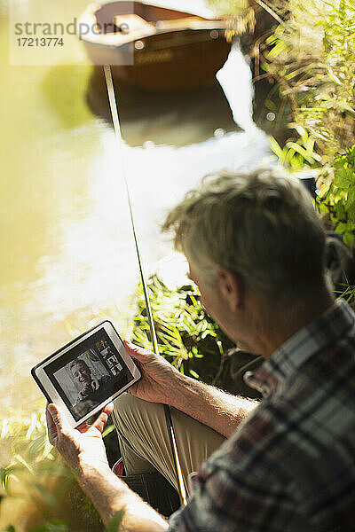 Mann Fliegenfischen und Video-Chat mit digitalen Tablet am Flussufer