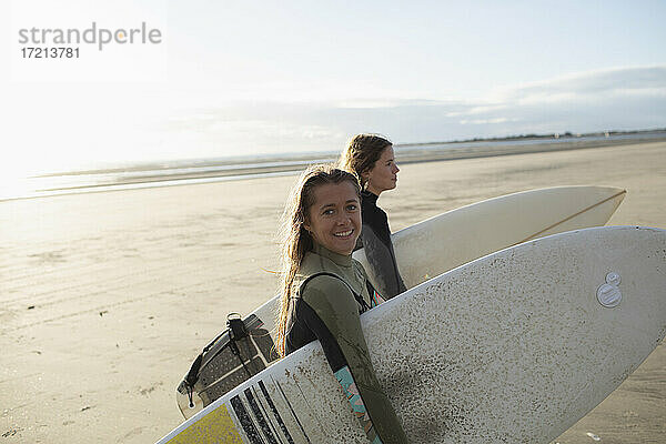 Porträt glücklich junge Surferinnen mit Surfbrettern auf sonnigen Strand