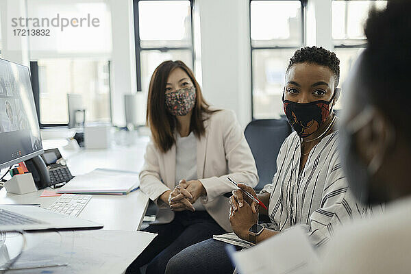 Geschäftsleute in Gesichtsmasken im Gespräch im Büro Sitzung