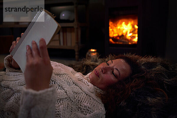 Frau entspannt Lesung Buch auf Decke an gemütlichen Kamin