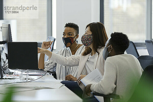 Geschäftsleute in Gesichtsmasken arbeiten am Computer im Büro