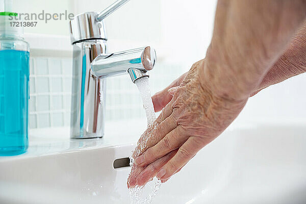 Close up ältere Frau Hände waschen am Waschbecken im Bad