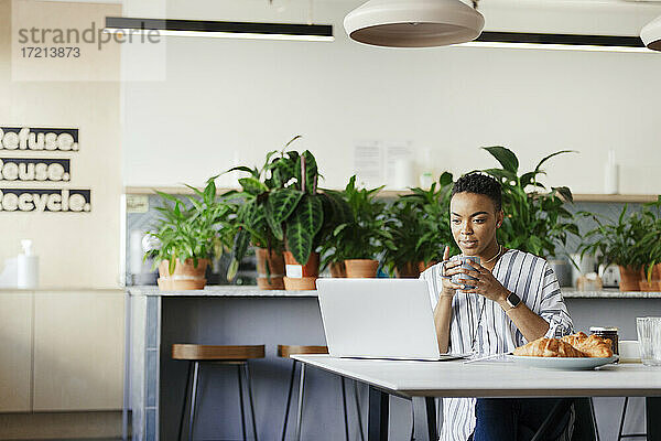 Geschäftsfrau mit Kaffee arbeiten am Laptop in Morgen Büro Lounge