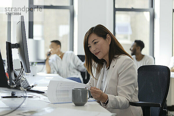 Geschäftsfrau Überprüfung Papierkram am Schreibtisch im Großraumbüro