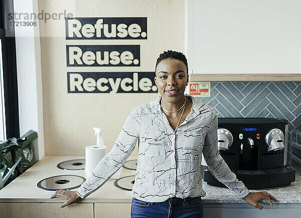 Porträt selbstbewusste Geschäftsfrau an Recycling-Behältern in Büroküche