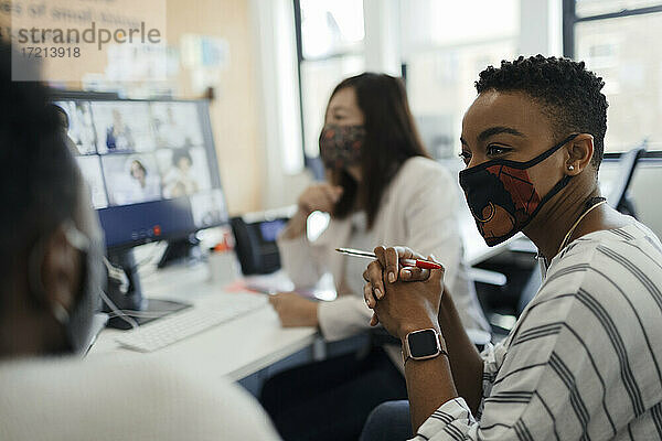 Geschäftsleute in Gesichtsmasken Videokonferenzen am Bürocomputer