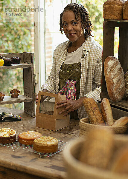 Porträt zuversichtlich weiblichen Bäcker Boxen Gebäck im Laden
