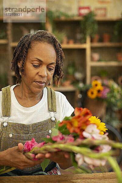 Weiblicher Florist arrangiert Blumen im Geschäft