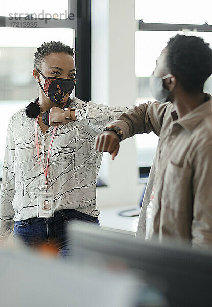 Geschäftsleute mit Gesichtsmasken Ellbogenstöße im Büro