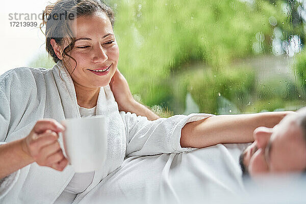 Glückliches Paar trinken Kaffee reden im Bett