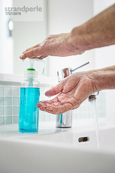 Ältere Frau beim Händewaschen mit Seife am Waschbecken im Bad