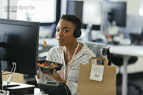 Porträt zuversichtlich Geschäftsfrau Essen Takeout Mittagessen im Büro Schreibtisch