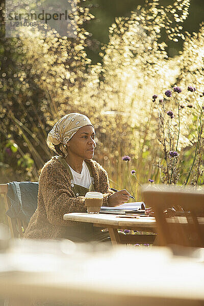 Frau mit Kaffee arbeiten an sonnigen Gartentisch