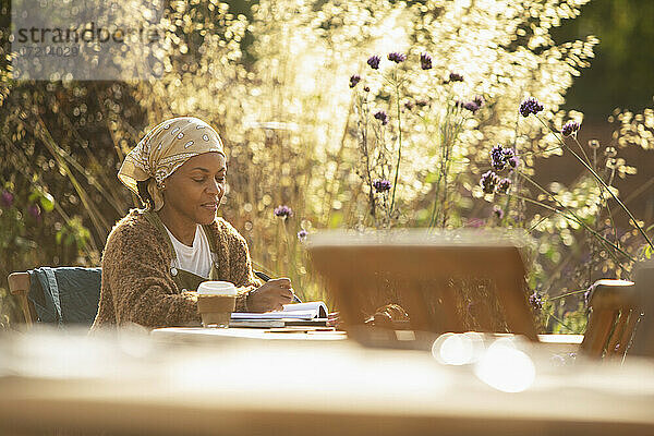 Frau arbeitet am Café Tisch in sonnigen Garten