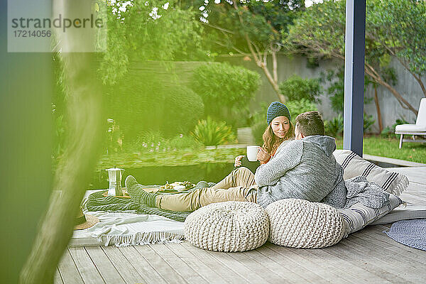 Paar entspannt auf Kissen mit Kaffee auf der Terrasse