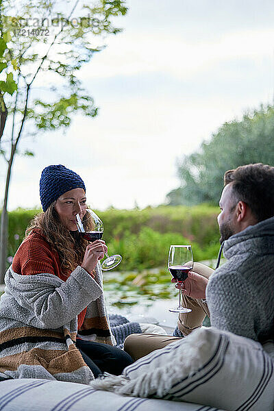 Paar trinkt Wein auf Terrassen-Kissen