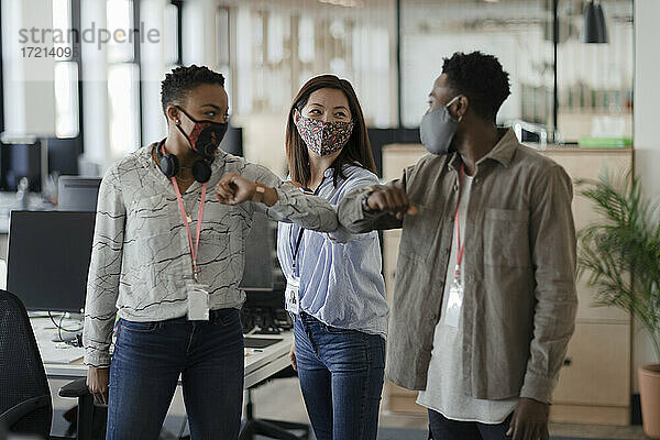Geschäftsleute mit Gesichtsmasken Ellbogenstöße im Büro