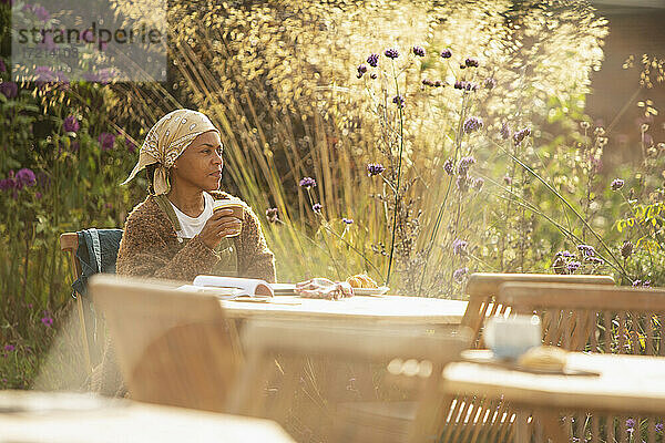 Frau mit Kaffee am sonnigen idyllischen Gartencafé Tisch