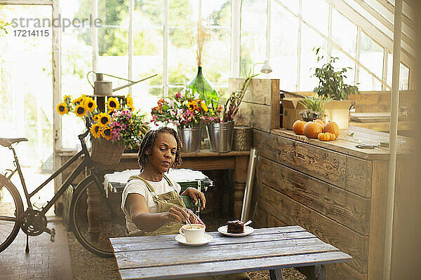 Weibliche Floristin genießt Kaffeepause am Tisch im Blumenladen