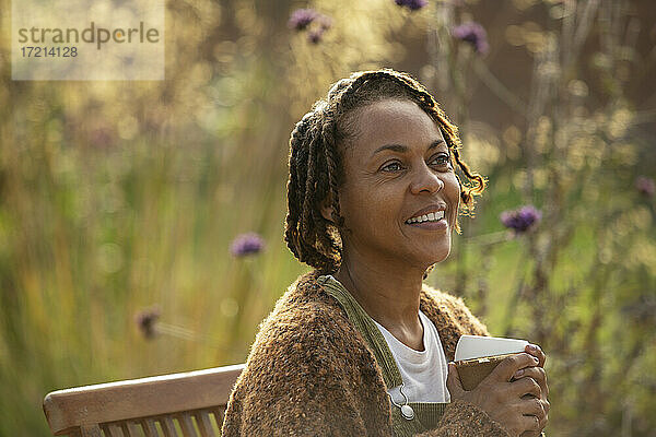 Glückliche Frau genießt Kaffee im sonnigen Garten
