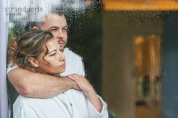 Serene zärtliches Paar umarmt bei regnerischen Fenster