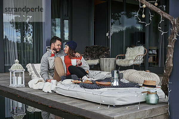 Zärtliches Paar entspannt sich mit Kaffee auf Terrassen-Kissen