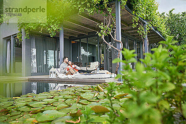 Zärtliches Paar entspannt mit Tee auf der Terrasse eines Luxushotels