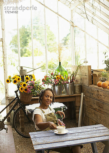 Porträt Bäckerin genießt Kaffeepause im Blumenladen