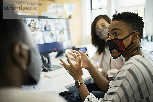 Geschäftsleute in Gesichtsmasken Videokonferenzen am Computer im Büro