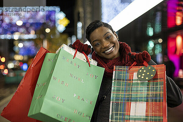 Porträt glückliche junge Frau Weihnachtseinkäufe in der Stadt in der Nacht