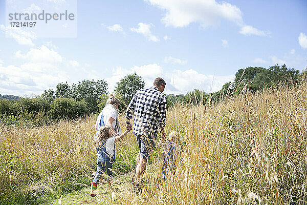 Familie hält Hände in sonnigen idyllischen ländlichen Feld zu Fuß