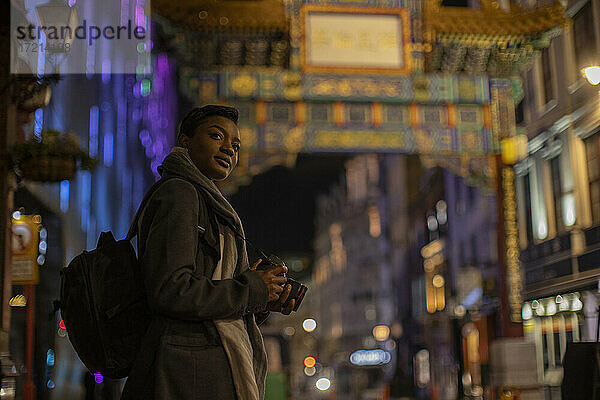 Junge Frau mit Digitalkamera am Chinatown Gate bei Nacht  London  UK