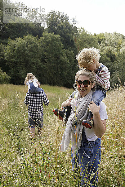 Porträt glückliche Mutter trägt Tochter auf den Schultern in ländlichen Feld