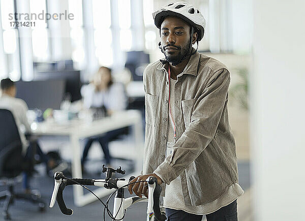 Geschäftsmann zu Fuß Fahrrad im Büro