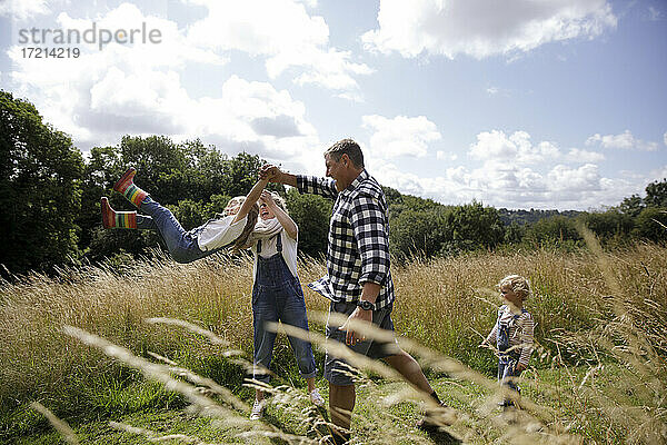 Glückliche Familie spielen in sonnigen idyllischen ländlichen Feld