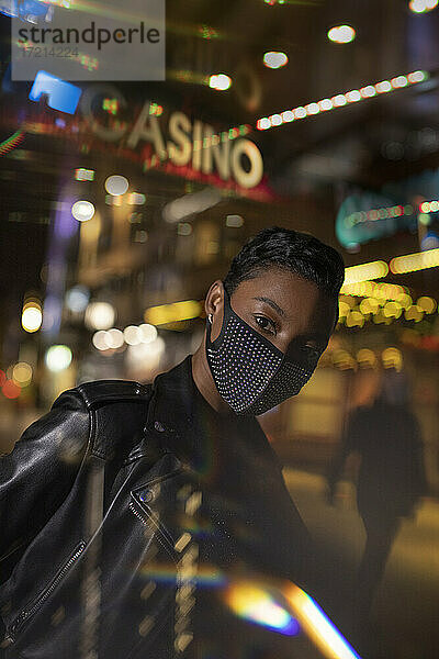Porträt selbstbewusste junge Frau in Gesichtsmaske auf Stadt Straße in der Nacht