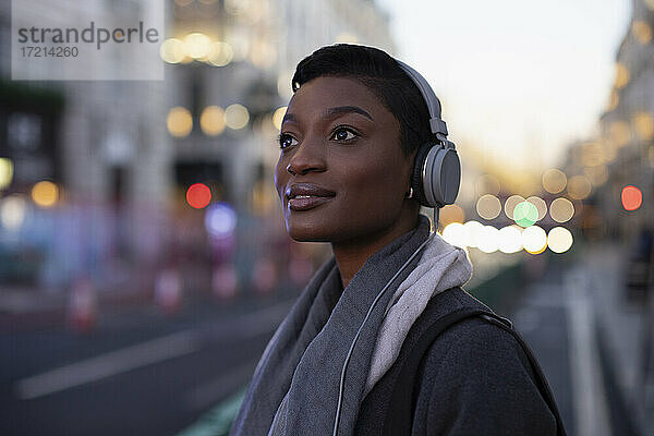 Schöne junge Frau in Kopfhörer auf der Straße der Stadt