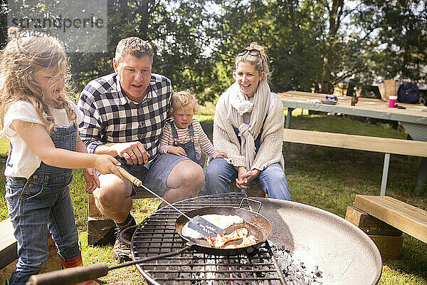 Glückliche Familie beim Grillen auf dem sonnigen Campingplatz