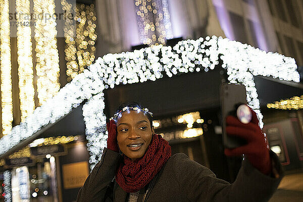 Junge Frau in Weihnachten Licht Stirnband nehmen selfie in der Stadt bei Nacht