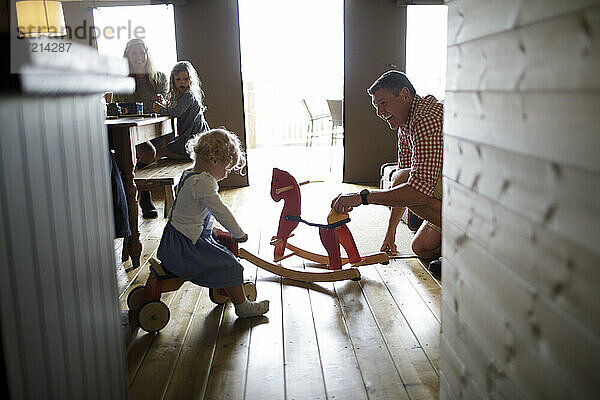 Familie mit Schaukelpferd und Spielzeug in der Hütte