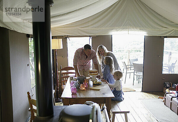 Glückliche Familie am Esstisch mit Erdbeerkuchen auf Jurtenzelt